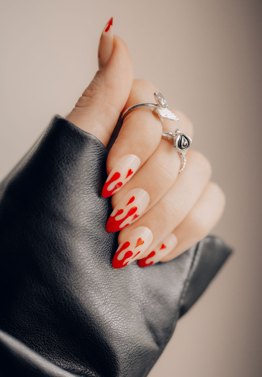 Drippy red painted finger nails cuffing a black leather sleave.